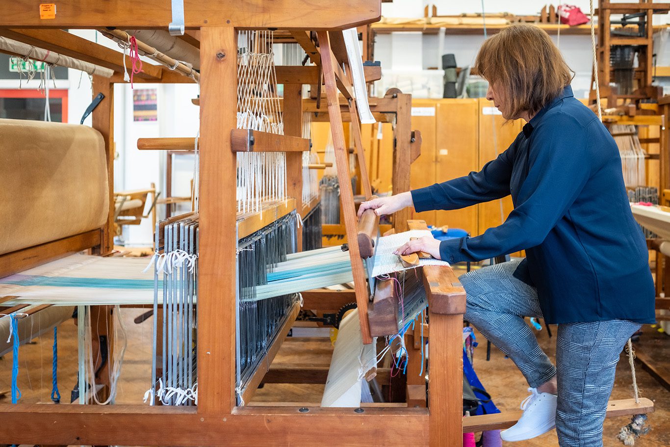 Image of Kathryn weaving on 16 shaft George Wood Dobby loom in Loughborough University weave shed.