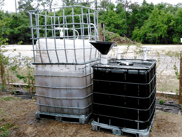 Two IBC agricultural containers arranged as a DIY Biodigester system. Note the very rough finish to the overall system.